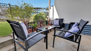 An outdoor seating area with two chairs and a table, surrounded by plants and a view of a building. - Lyrebird Hideaway: Pet Friendly, Peaceful & Private Retreat (Lakes Entrance)
