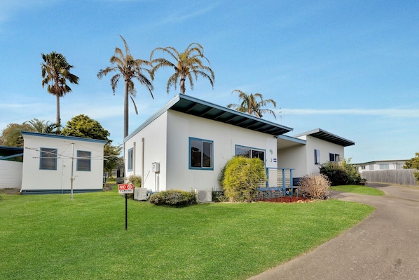 A single-story mobile home with a white exterior and blue trim, a front porch, and a small attached garage.