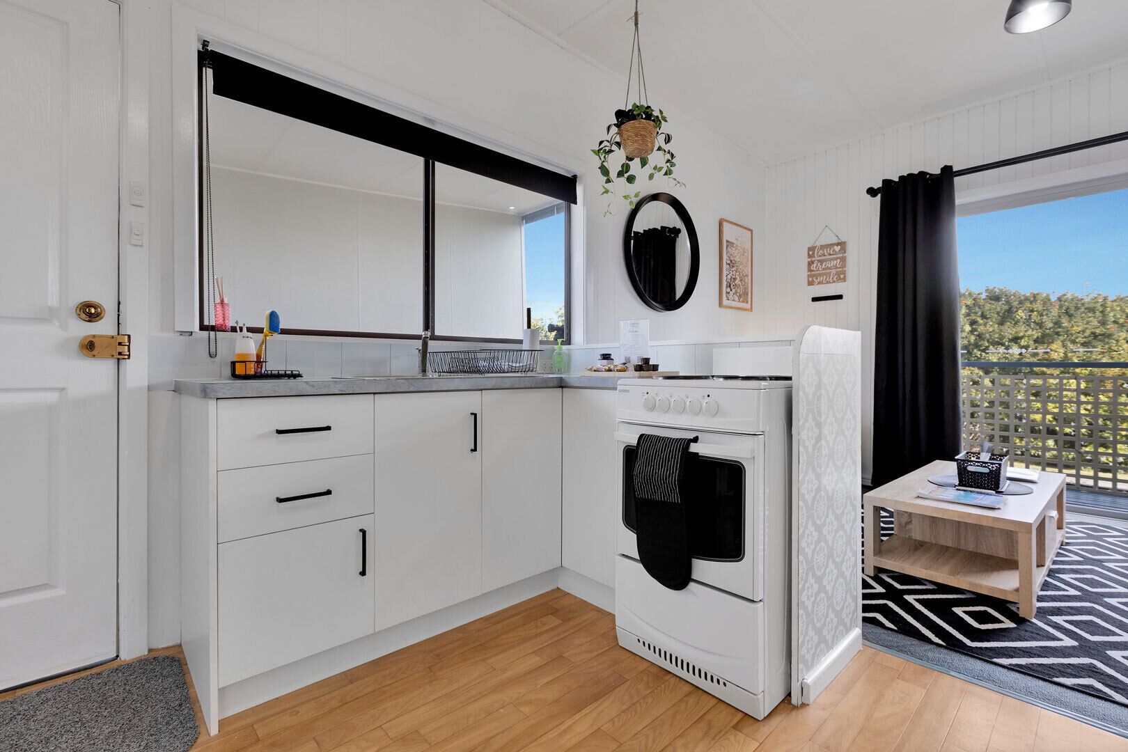A modern kitchen with white cabinets, a built-in oven, and a small dining area with a table and chairs.