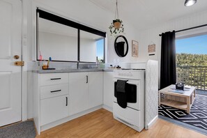 A modern kitchen with white cabinets, a built-in oven, and a small dining area with a table and chairs.