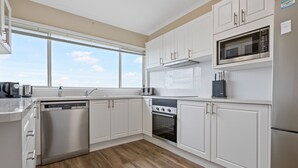 Una cocina moderna con armarios blancos, lavavajillas de acero inoxidable, horno y microondas.