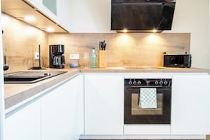 A modern kitchen with white cabinets, a built-in oven, a coffee maker, and a microwave. - Tide Resort 2a DG - Sauna. Balcony. Meernah. (Tossens)