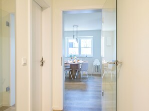 A modern interior with a dining area, a glass door leading to another room, and a visible light switch on the wall. - Tide Resort 2a DG - Sauna. Balcony. Meernah. (Tossens)