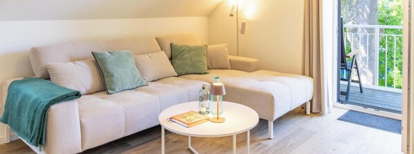 A cozy room with a sofa, a small table, and a view through a door. - Tide Resort 2a DG - Sauna. Balcony. Meernah. (Tossens)
