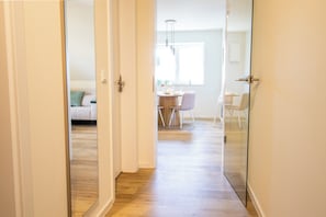 A hallway leading to a dining area with a table and chairs, a sofa in the background, and a glass partition. - Tide Resort 2a DG - Sauna. Balcony. Meernah. (Tossens)