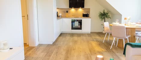 Una cocina moderna con horno empotrado y comedor con mesa y sillas.
