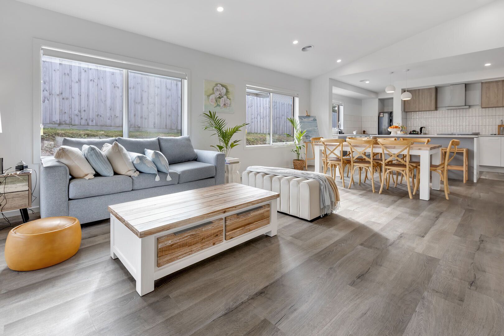 Een moderne woonkamer met een bank, salontafel en een eethoek met stoelen.