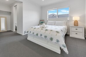 A bedroom with a bed, a nightstand, a lamp, a window with a view, and a door leading to another room. - Coast and Canopy is the perfect place to slow down and reconnect (Eagle Point)