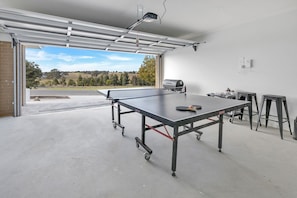 A ping pong table in a garage with a view to the outside. - Coast and Canopy is the perfect place to slow down and reconnect (Eagle Point)