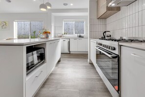 A modern kitchen with white cabinetry, a built-in oven, a stove, and a dishwasher. - Coast and Canopy is the perfect place to slow down and reconnect (Eagle Point)