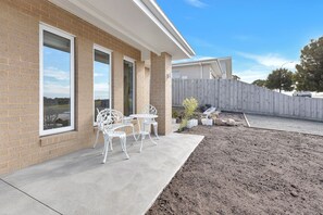 Une terrasse avec des meubles d’extérieur, un mur en briques et une clôture en bois.