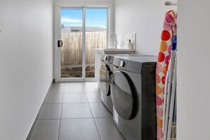 A laundry room with a washing machine, dryer, and a small sink. - Coast and Canopy is the perfect place to slow down and reconnect (Eagle Point)