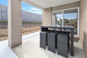 An outdoor patio with a glass-top table and four square chairs. - Coast and Canopy is the perfect place to slow down and reconnect (Eagle Point)