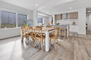 Eine moderne Küche mit weißen Schränken, einem Holztisch und Stühlen.