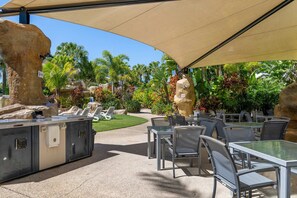 Ein Außenbereich mit Patio, einem Grill, Lounge-Stühlen und Tischen unter einer großen Markise.