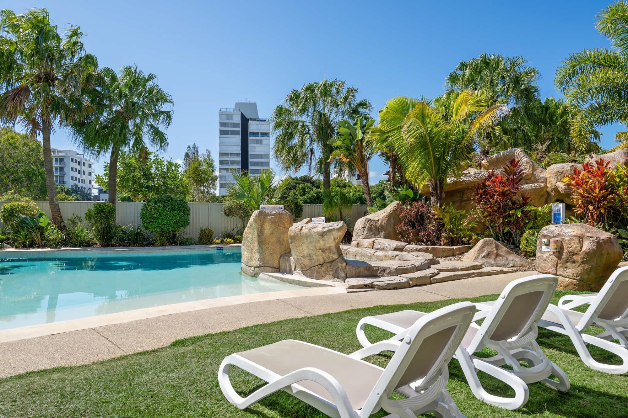 A pool area with lounge chairs and tropical landscaping.