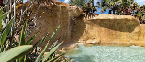 A natural rock formation with a clear pool and a waterfall.