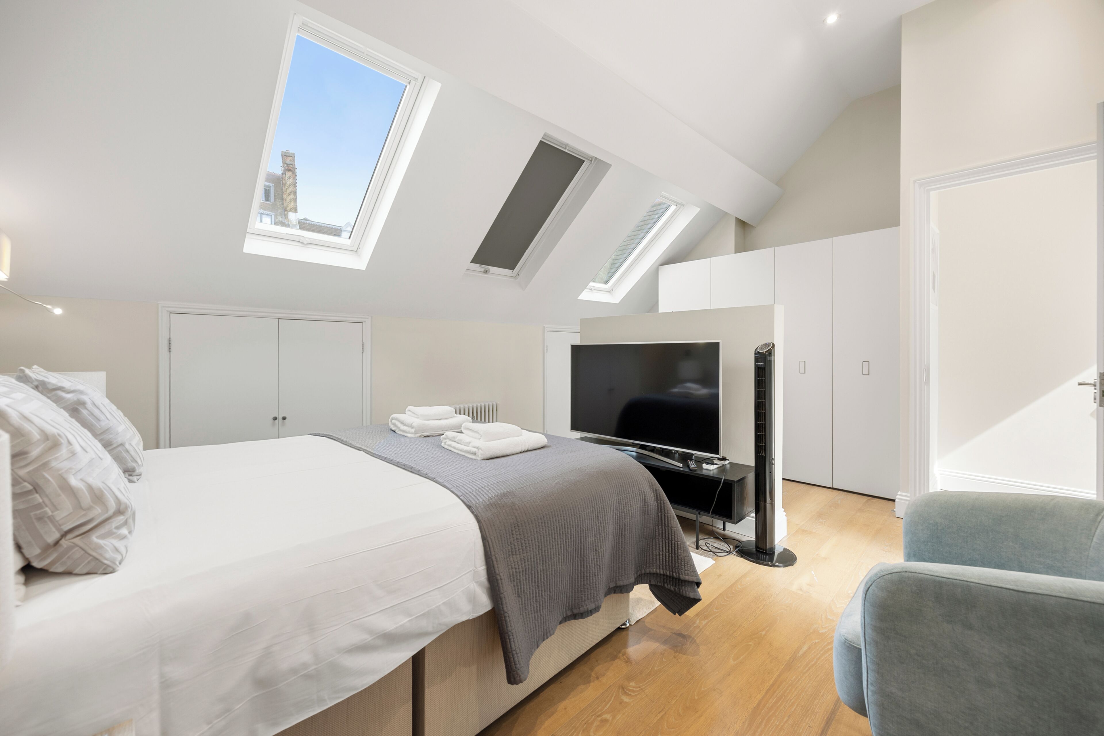 A modern bedroom with a bed, a television, and a seating area.