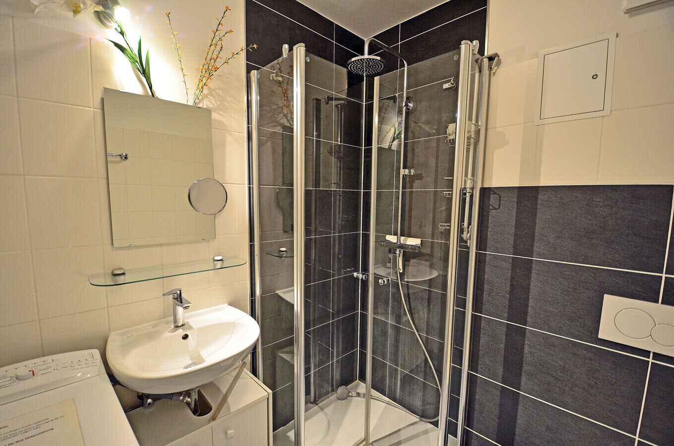 A modern bathroom with a glass-enclosed shower, a white sink, and a mirror above it.