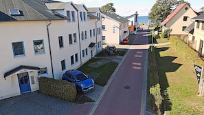 Eine Wohnstraße mit Häusern, ein blaues Auto vor einem Haus geparkt und ein rotes Auto weiter hinten auf der Straße.