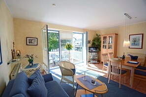 Ein Wohnzimmer mit Sofa, einem Esstisch mit Stühlen, einem Fernseher und einem Balkon mit Blick.