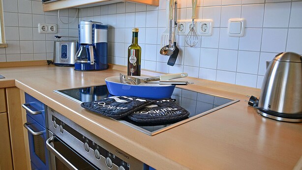 A kitchen with a built-in stove, a coffee maker, and various utensils. - Just 50 meters from the sandy Baltic Sea beach, Wi-Fi, washing machine, accommodates up to 4 people, with a balcony (Glowe)
