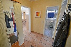 Ein Flur mit Spiegel, Kleiderhaken und einer Tür zu einem Badezimmer.