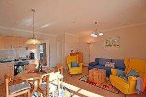 A living room with a sofa, chairs, a coffee table, and a dining area with a table and chairs. - Just 50 meters from the sandy Baltic Sea beach, Wi-Fi, washing machine, accommodates up to 4 people, with a balcony (Glowe)