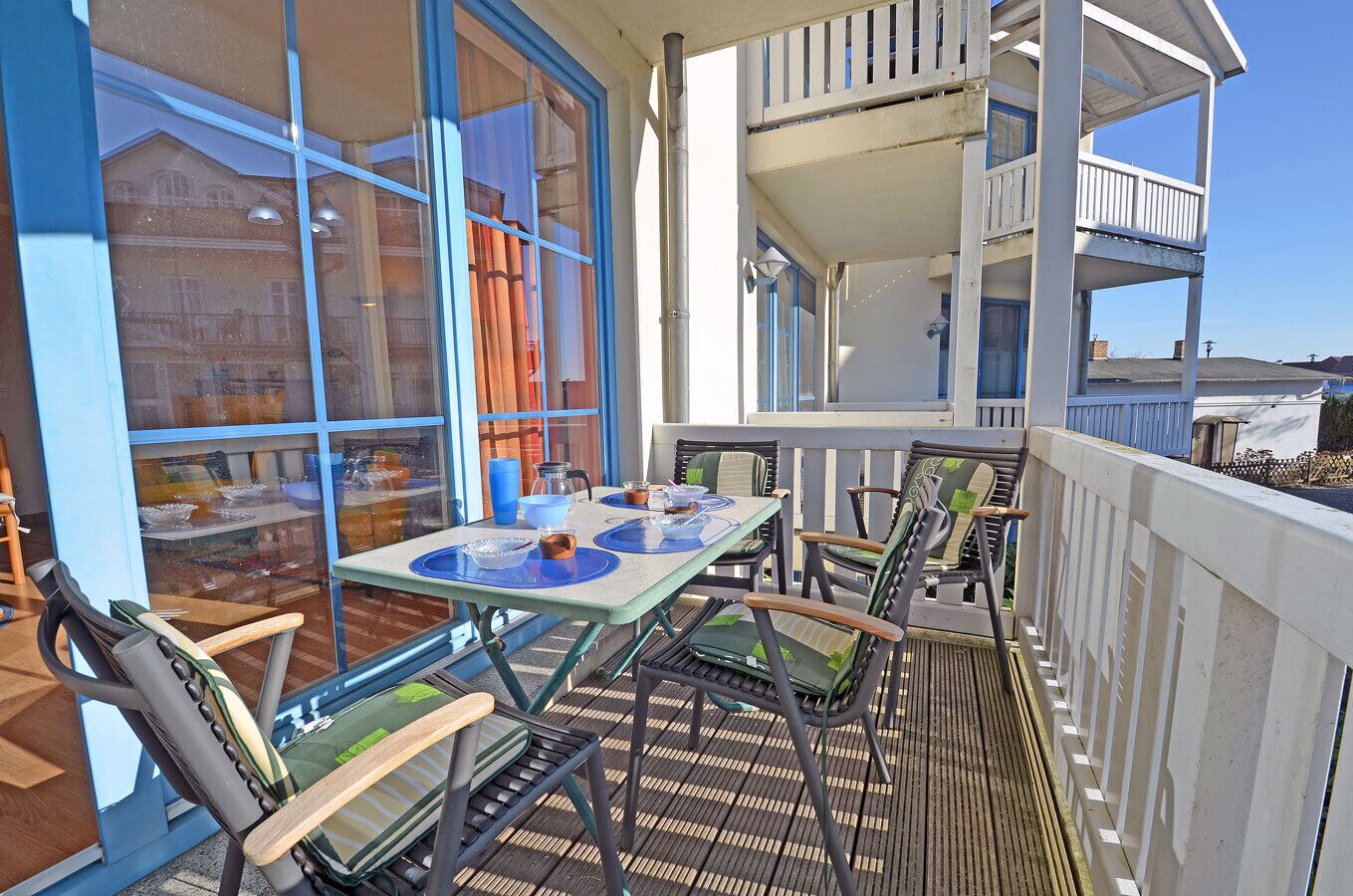 Un espace extérieur aménagé pour prendre les repas, avec une table dressée pour deux personnes, entourée de chaises.