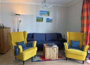 Un salon comprenant un canapé, deux fauteuils, une table basse et une lampe.