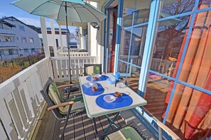 A balcony with a table set for two, a chair, and a hanging umbrella. - Just 50 meters from the sandy Baltic Sea beach, Wi-Fi, washing machine, accommodates up to 4 people, with a balcony (Glowe)