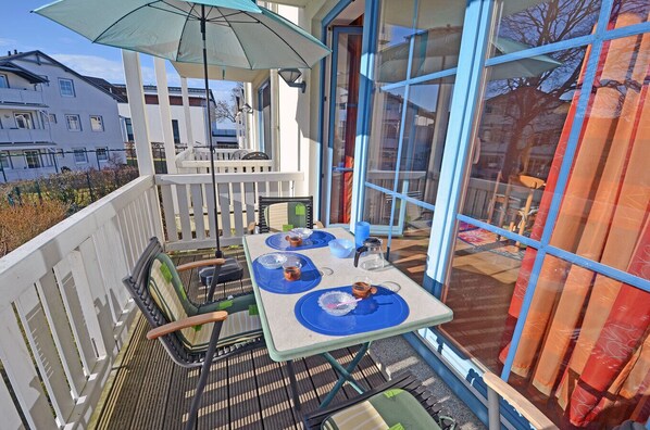 Ein Balkon mit einem Tisch für zwei Personen, einem Stuhl und einem Sonnenschirm.