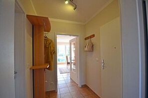 A hallway with a wooden door, a coat rack, and a wall-mounted bag holder. - Just 50 meters from the sandy Baltic Sea beach, Wi-Fi, washing machine, accommodates up to 4 people, with a balcony (Glowe)