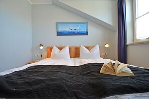 Ein Schlafzimmer mit einem Bett, einem Segelboot-Gemälde und einem fenster mit Vorhängen.