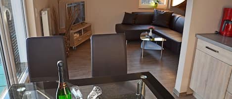 Un salon moderne avec un canapé, une table basse et un coin repas doté d’une table en verre.