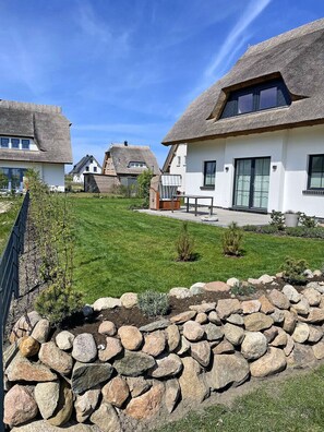 A residential area with thatched-roof houses, a stone wall, and a well-maintained lawn. - Fully fenced, located between the Bodden and a natural beach, with a sauna and internet access (Dranske)