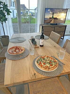 Ett matbord med två pizzor, en flaska och glas.