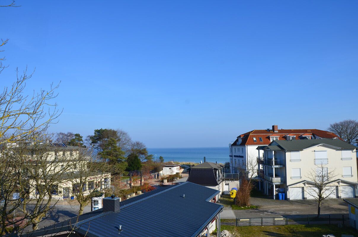 A coastal residential area with buildings, a clear sky, and a view of the sea.