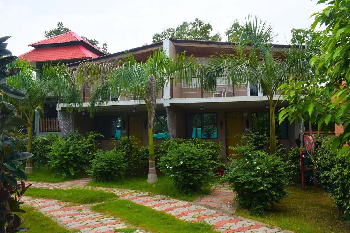 A building with a red roof, surrounded by lush greenery and a paved pathway.