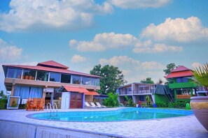 Un área de piscina con cielo despejado, una piscina y edificios con tejados rojos.