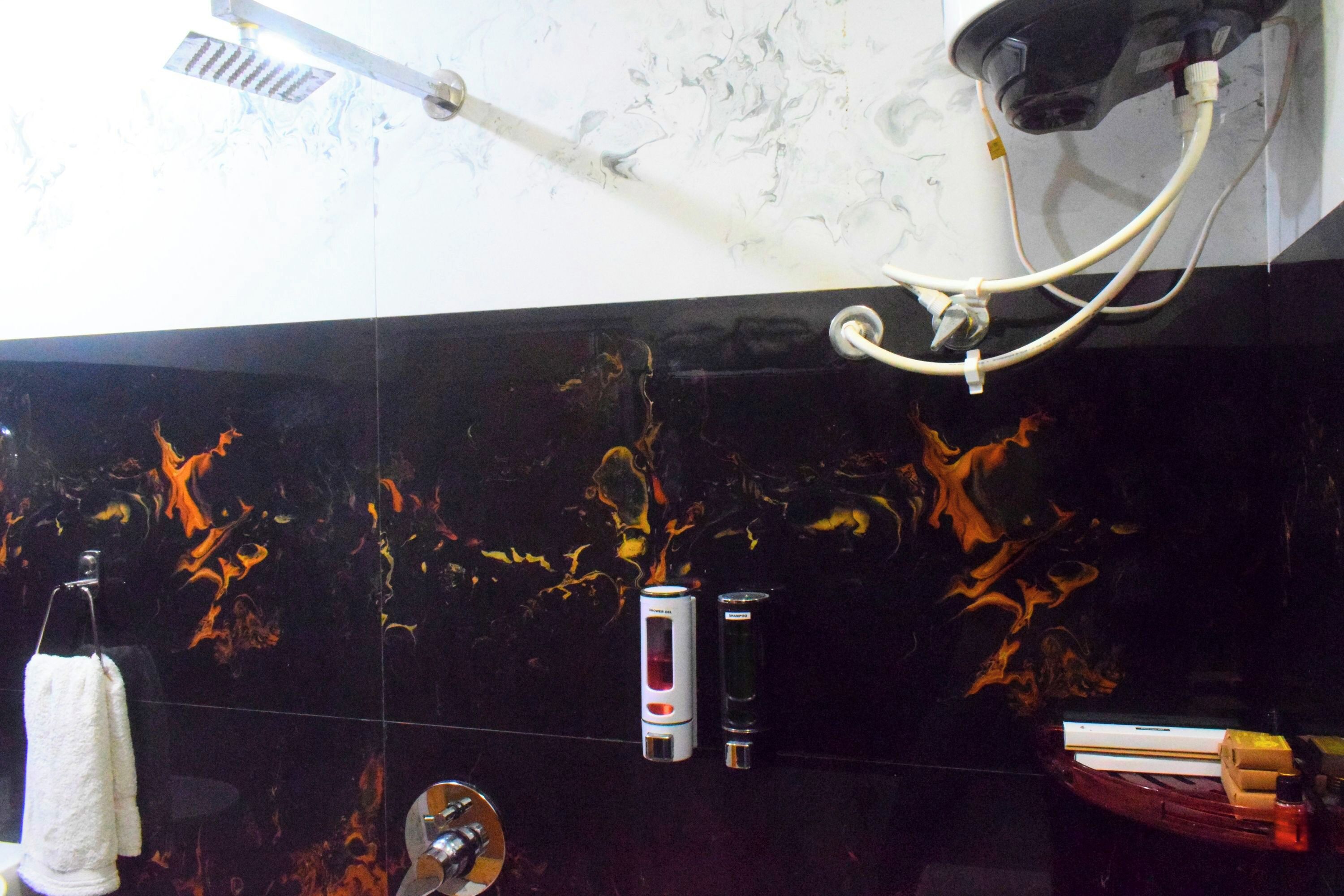 Une salle de bain avec un mur en marbre noir, une pomme de douche, un pommeau de douche amovible et un porte-serviettes.