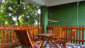 Un balcon avec un sol à carreaux, des chaises en bois et une table.