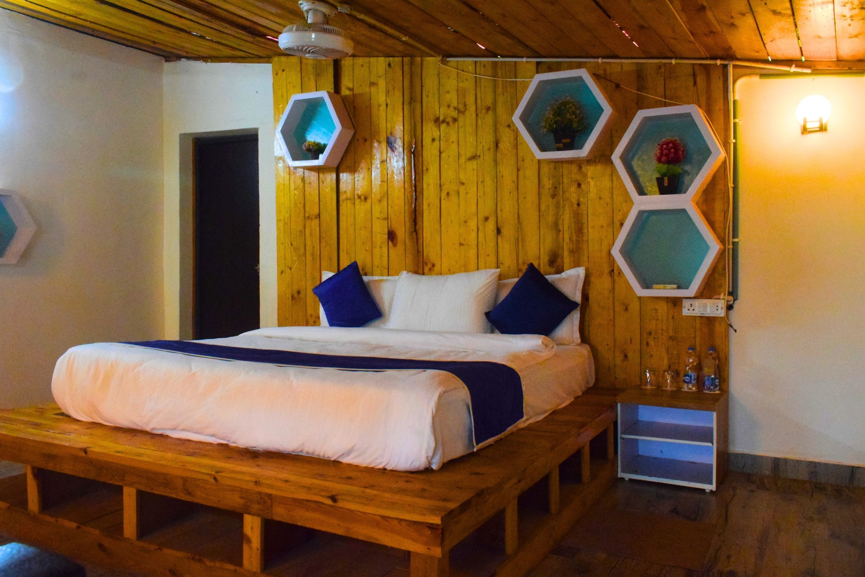 A wooden bed with a white and blue bedding set, a wooden bench, and hexagonal wall decorations.