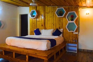 A wooden bed with a white and blue bedding set, a wooden bench, and hexagonal wall decorations.