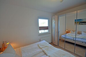 Une chambre avec un lit simple, une fenêtre, un radiateur et une armoire.