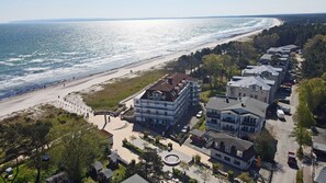 Un quartier résidentiel situé sur la côte, avec accès à la plage, des immeubles à plusieurs étages et une promenade pavée longeant la plage.