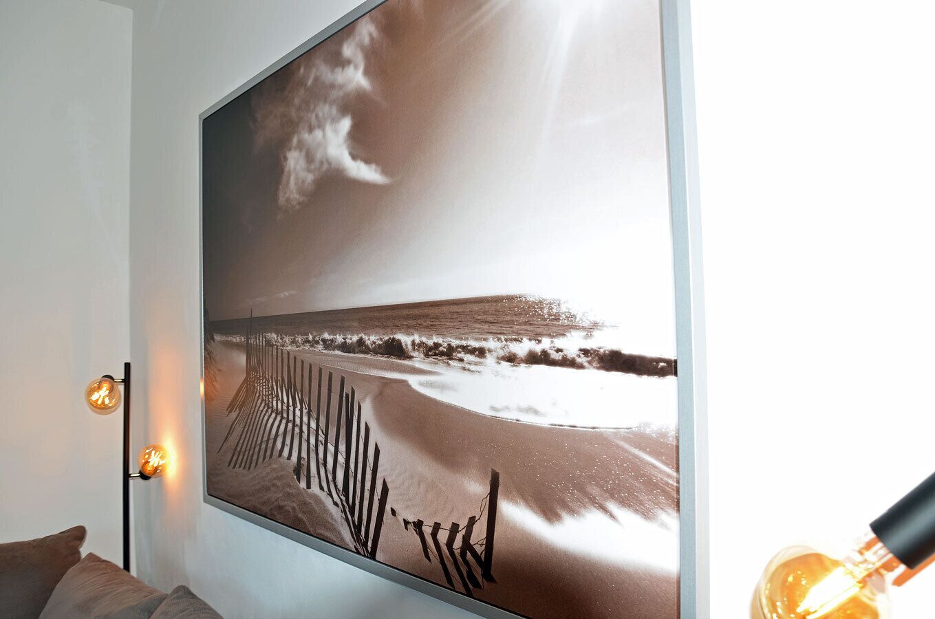 A wall-mounted television displaying a beach scene with waves and a fence.
