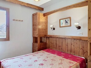 Ett rum med träpanel på väggarna, en säng, en vägglampa och en inramad tavla.