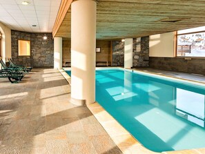 An indoor swimming pool with stone walls and a tiled floor. - Cozy apartment with balcony - 4 guests (La Toussuire)