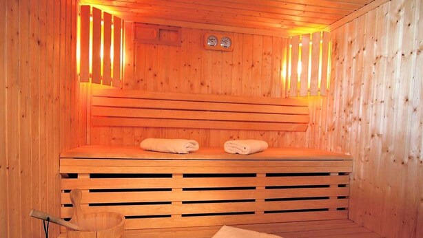 A wooden sauna with two benches, a wooden bucket, and towels. - Cozy apartment with balcony - 4 guests (La Toussuire)